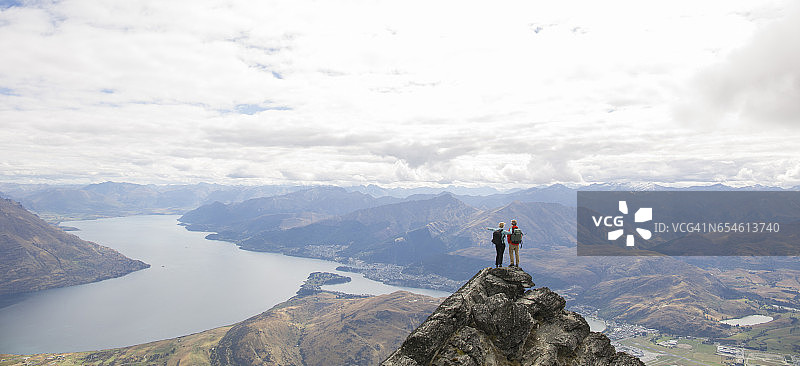 徒步旅行的情侣站在山顶上，向外眺望图片素材
