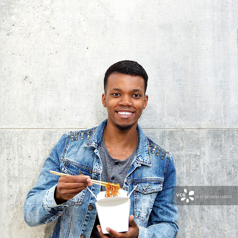 微笑的非裔美国人与面条在快餐盒图片素材