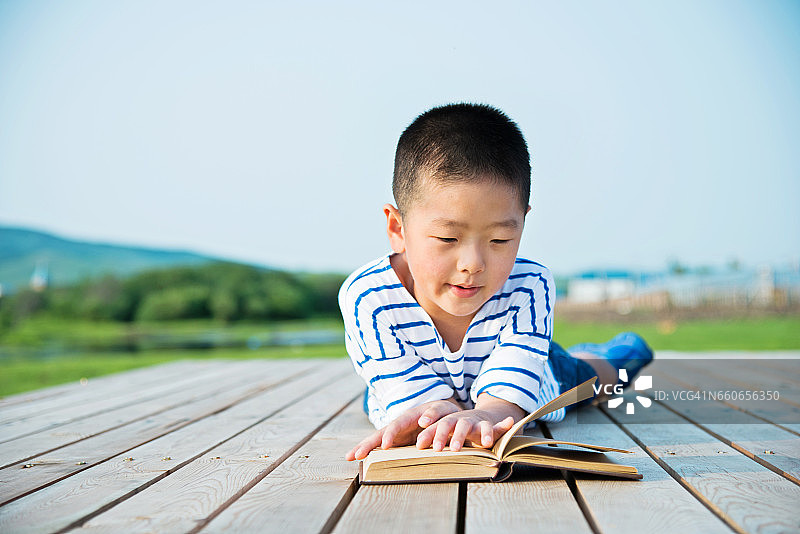 一个亚洲小男孩在大自然中读书图片素材