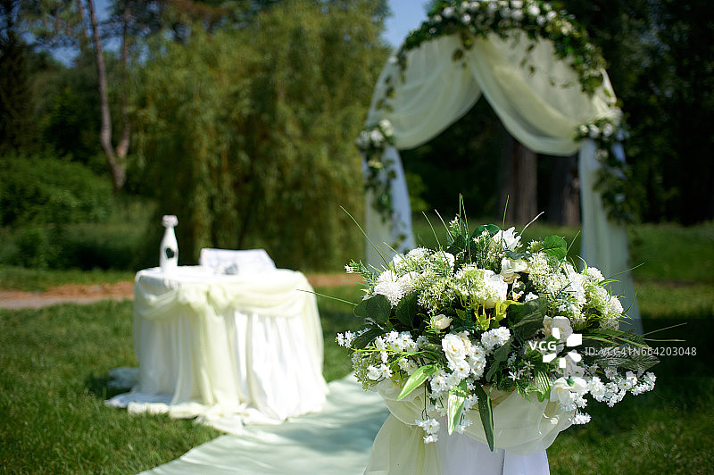 美丽的白色婚礼拱门装饰着白色和绿色的鲜花在户外图片素材