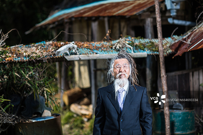 梳着雷鬼辫、穿着西装的日本老男人在乡村背景下图片素材