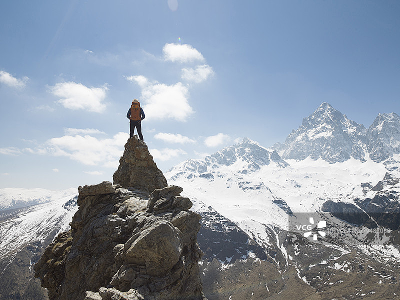 一名男性登山运动员站在山巅，俯瞰山谷图片素材