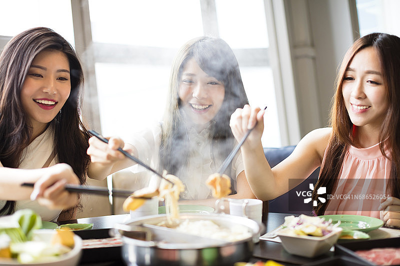 快乐的年轻女性团体吃火锅图片素材