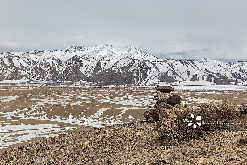中国塔什库尔干，白雪皑皑的山脉旁的堆尼石图片素材