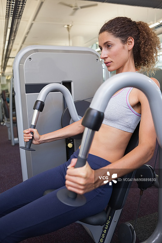 用举重机锻炼手臂的健康女性图片素材