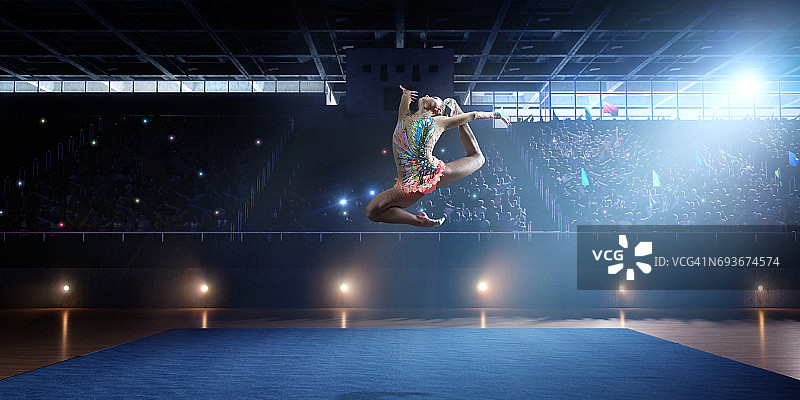体操女运动员在大型专业舞台上跳跃图片素材