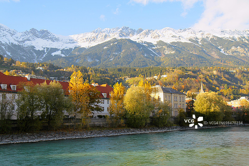 因斯布鲁克酒店的河岸建筑立面和田园诗般的秋天，北蒂罗尔雪山覆盖的卡温德尔山脉在日出，奥地利图片素材