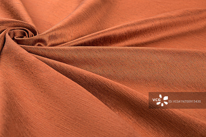 橙色背景的豪华布料或波浪褶皱的垃圾丝绸纹理缎天鹅绒图片素材