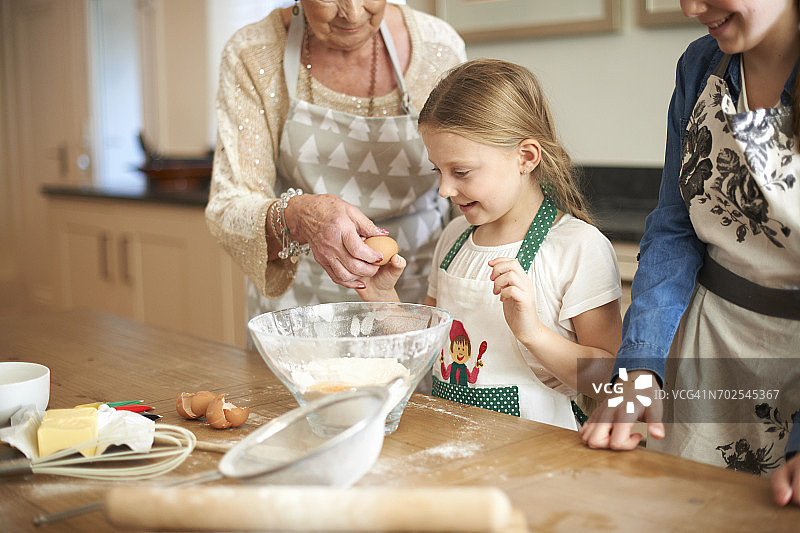 老年妇女和孙女们打鸡蛋做饼干图片素材