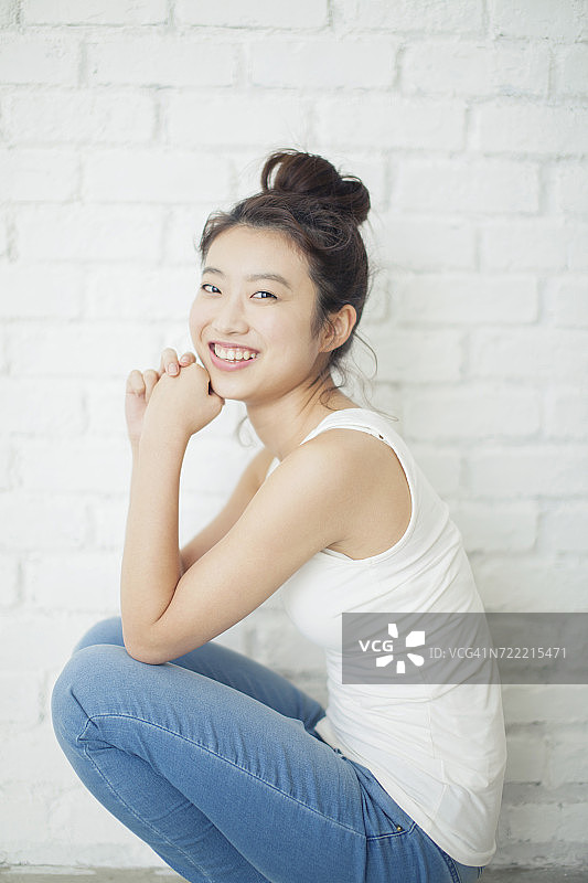一个年轻女子的画像，坐在墙边图片素材