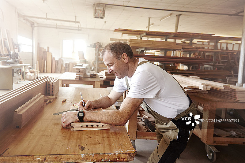 男木匠在工作台上用铅笔在木头上做记号图片素材