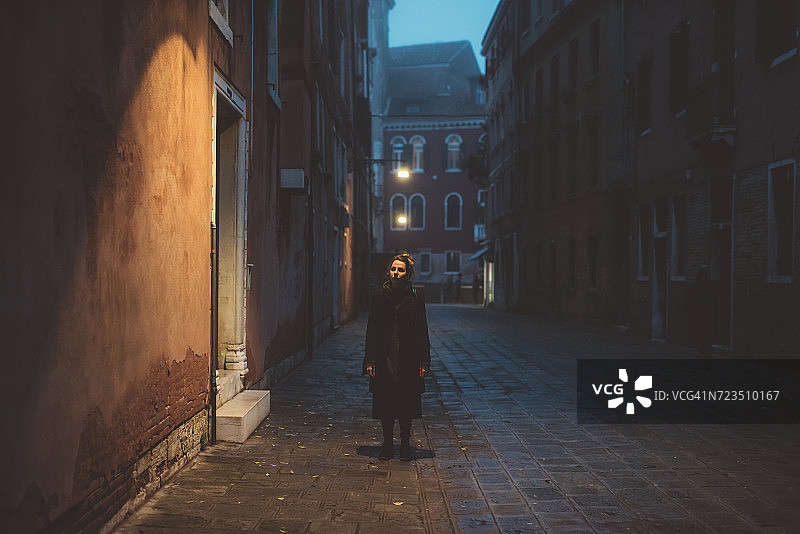 年轻女子站在街道上黄昏的肖像，威尼斯，意大利图片素材