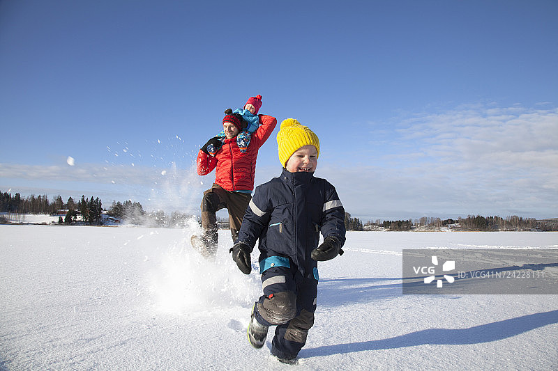 父亲和两个儿子在雪地里玩耍图片素材