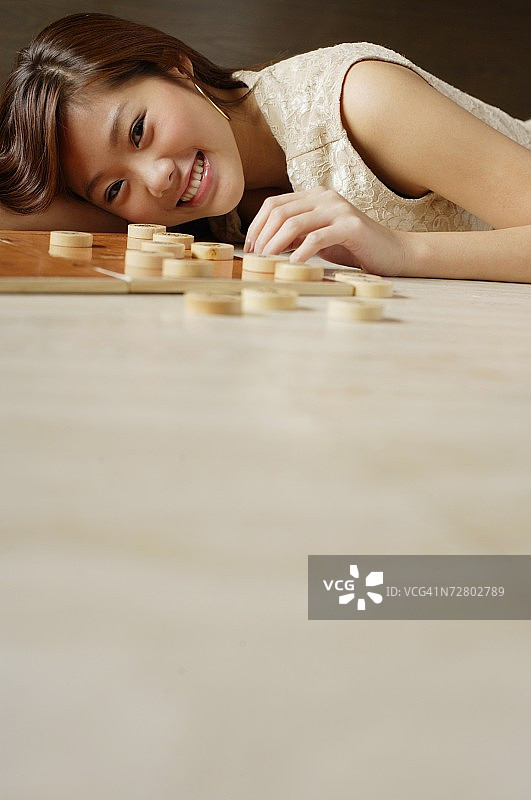 女人躺在地板上，中国棋子就在她旁边图片素材