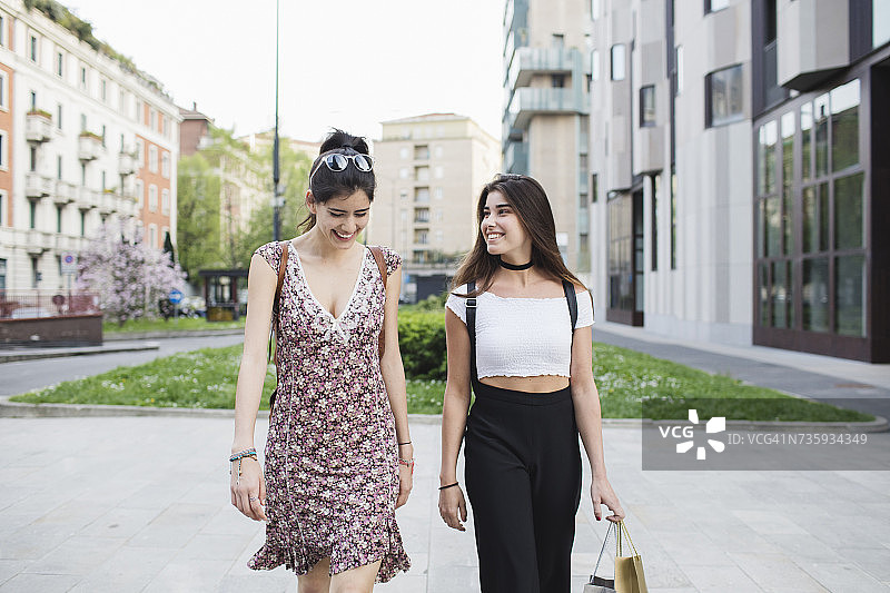 两个快乐的年轻女人走在城市里图片素材