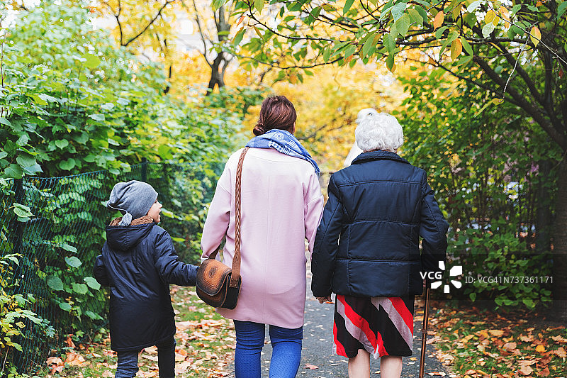 后视图的老年妇女与女儿和曾孙在公园散步在秋天图片素材
