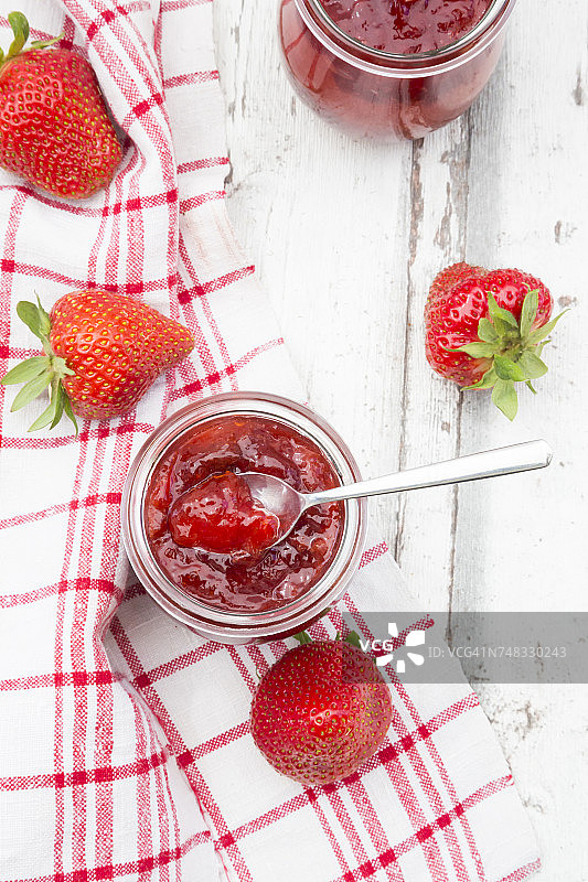 一杯自制的草莓酱，厨房毛巾和白木头上的草莓图片素材