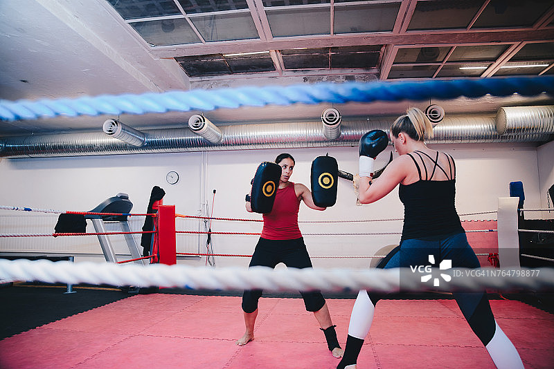 女运动员在拳击馆里和教练一起练习跆拳道图片素材