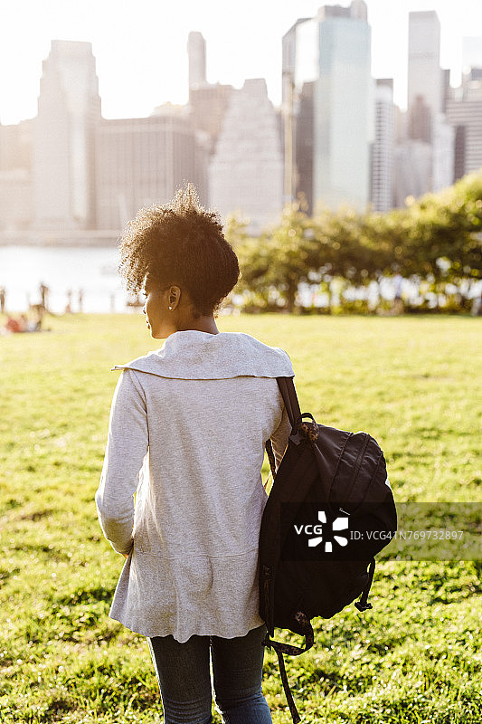 美国，纽约，布鲁克林，一个女人站在草地上看天际线图片素材