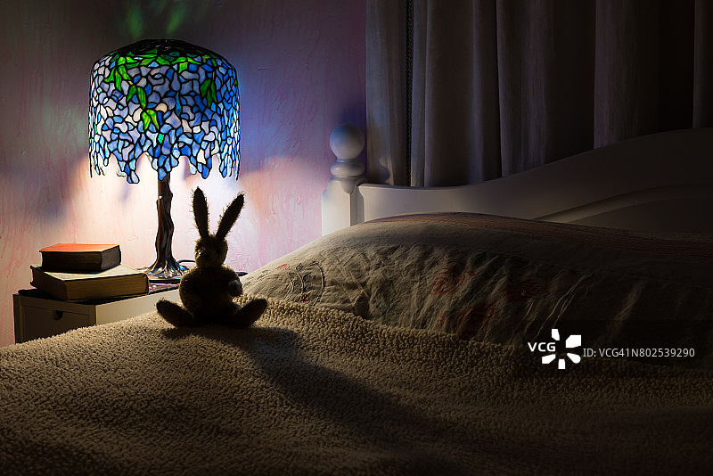 玩具兔子在卧室里被灯照亮了。图片素材