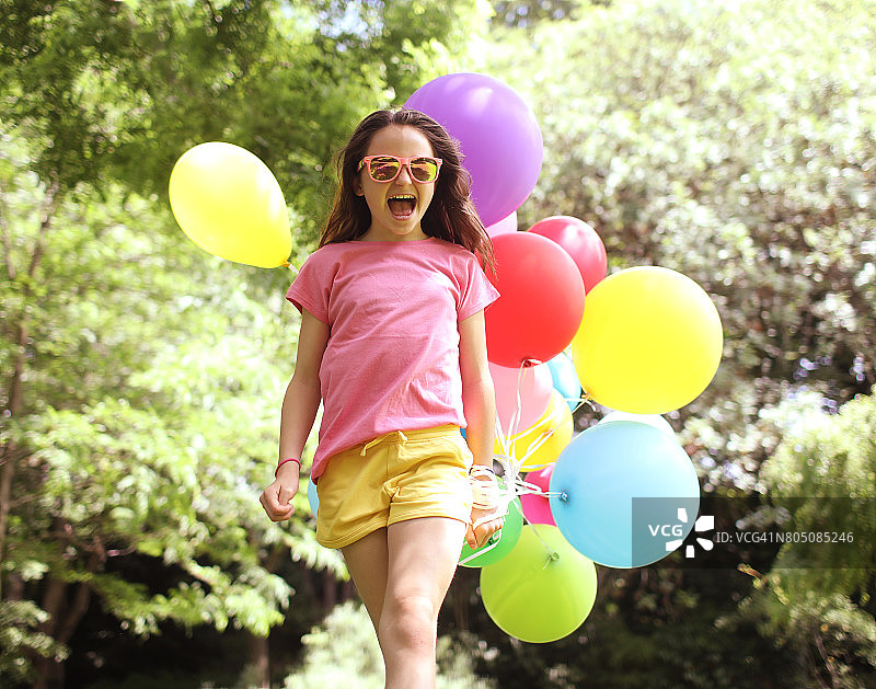 一个10岁的小女孩在公园里拿着气球图片素材