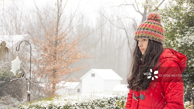 白雪中戴着红色羊毛帽和外套的女孩图片素材