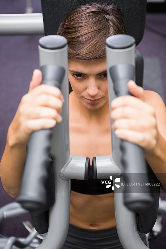 深褐色头发的女人用举重机锻炼手臂图片素材