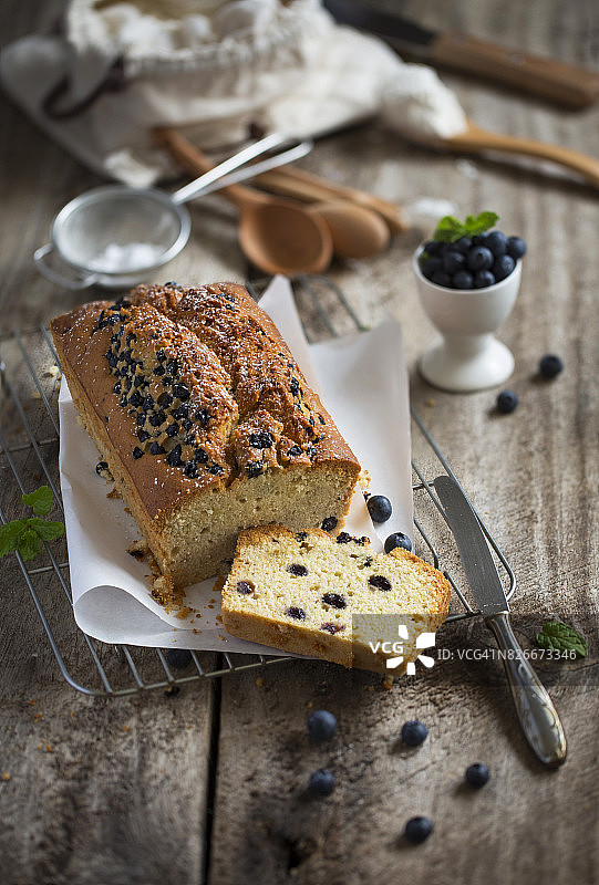 新鲜出炉的蓝莓切片蛋糕面包放在质朴的木制厨房柜台桌上。图片素材