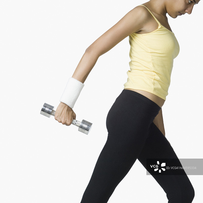 一个手持哑铃锻炼的年轻女子侧影图片素材