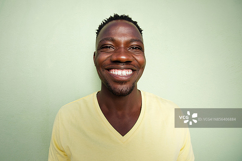 有趣的非洲年轻人对着绿色的墙微笑图片素材