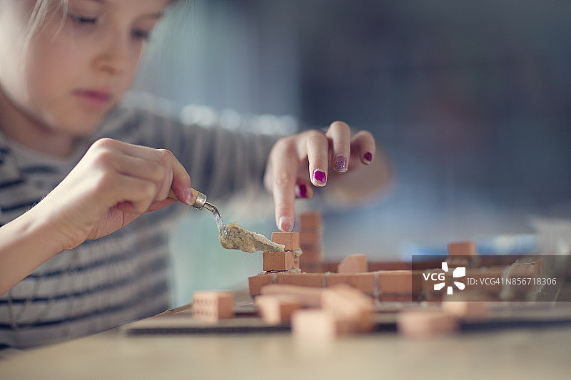 女孩(10-11)用砖块建造微型房子图片素材