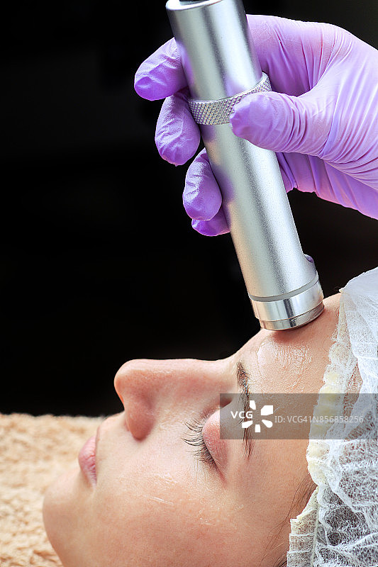针皮肤病。美容师在一个女人的脸上进行针刺皮肤科治疗图片素材