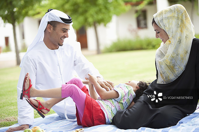 阿拉伯父母的女儿躺在母亲的腿上。图片素材