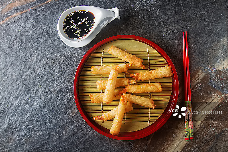 虾仁炸卷，配甜辣酱和筷子。黑暗的背景。图片素材
