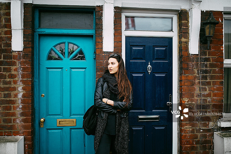 一个年轻女子在家门口等出租车图片素材