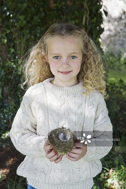 小女孩抱着鸟巢摆姿势图片素材