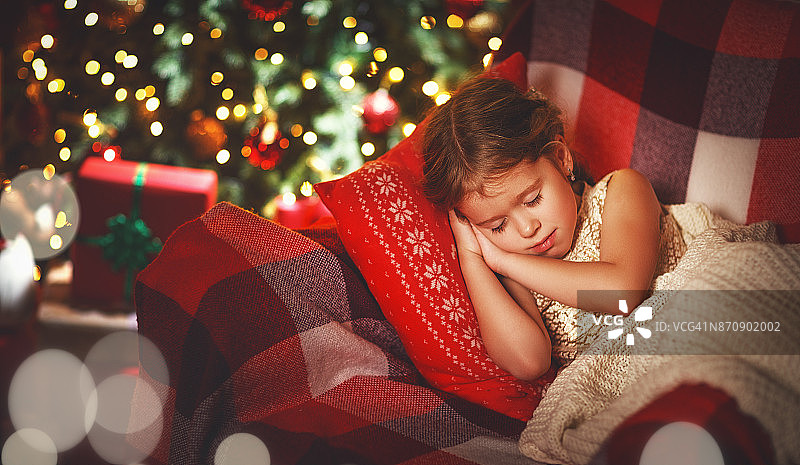 一个小女孩在圣诞树旁睡觉图片素材