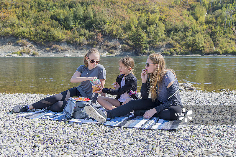 三姐妹分享野餐河畔海滩图片素材