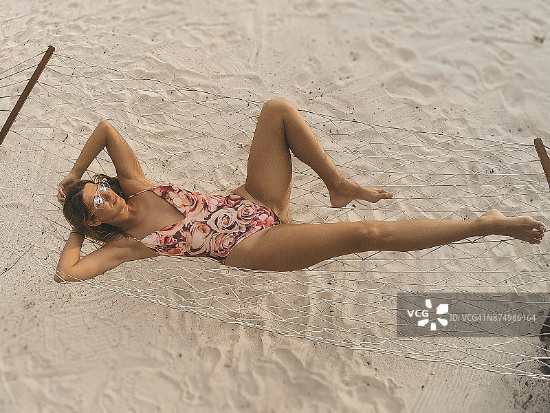 在热带海滩的吊床上放松的健康女人图片素材