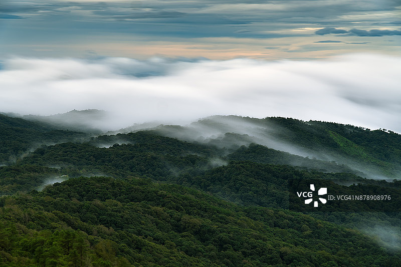 云在森林上移动，山上的天空朦胧，低快门速度效果。图片素材