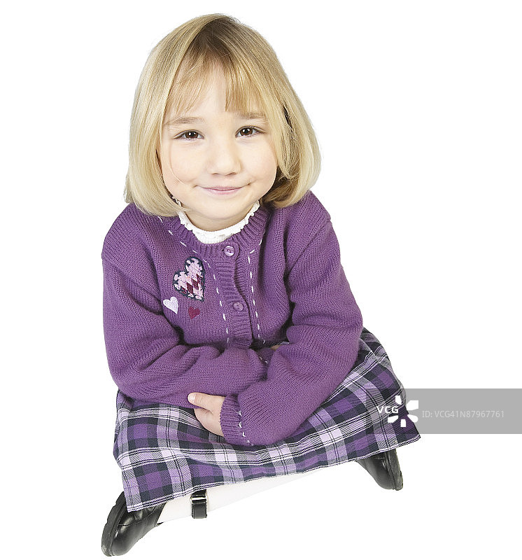 年轻的金发女孩盘腿坐在地板上微笑着图片素材