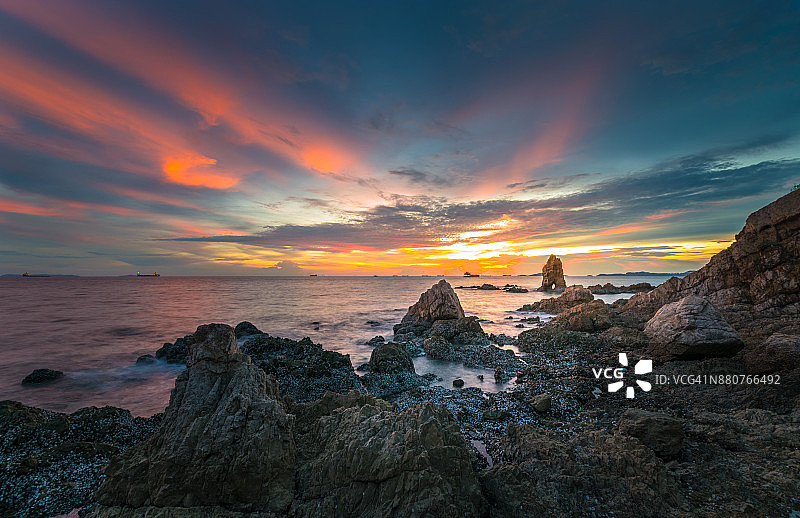 日落时，海滩上的岩石对着戏剧性的天空图片素材