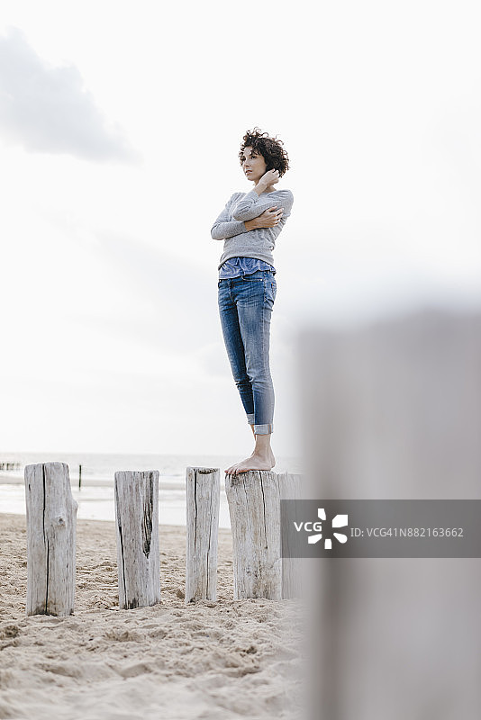 一个女人站在沙滩上的木桩上图片素材