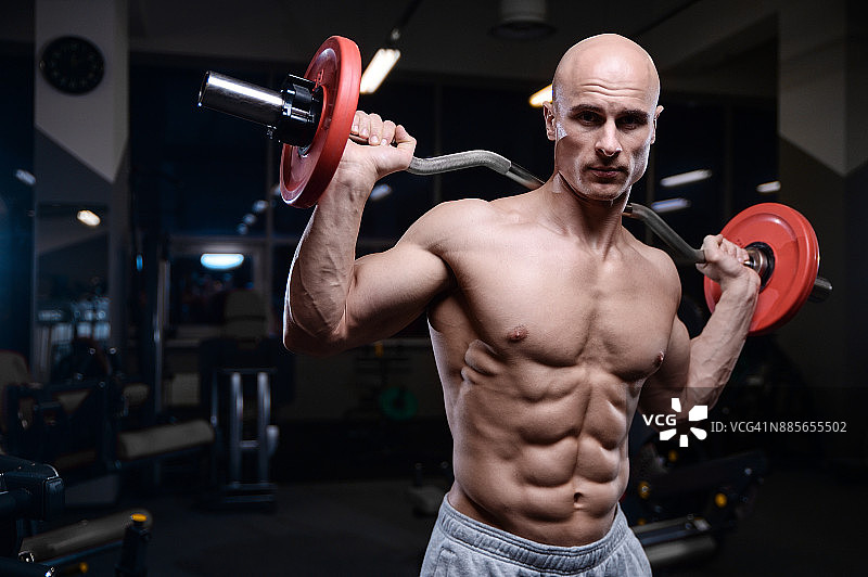 野蛮强壮的健美运动员用哑铃锻炼肌肉图片素材