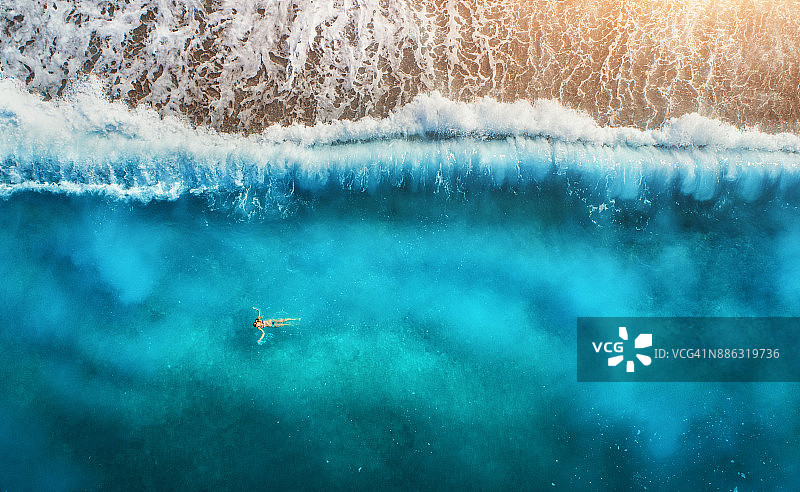 鸟瞰游泳女子在地中海在Oludeniz，土耳其。美丽的夏日海景与年轻的女孩，蓝色的水，海浪和沙滩日落。俯视图从飞行的无人机。假期图片素材