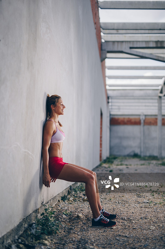 快乐的运动女人做墙坐上运动训练。图片素材