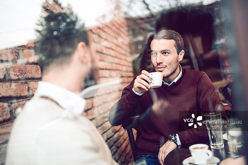 两个微笑的朋友在喝咖啡和在咖啡馆社交图片素材