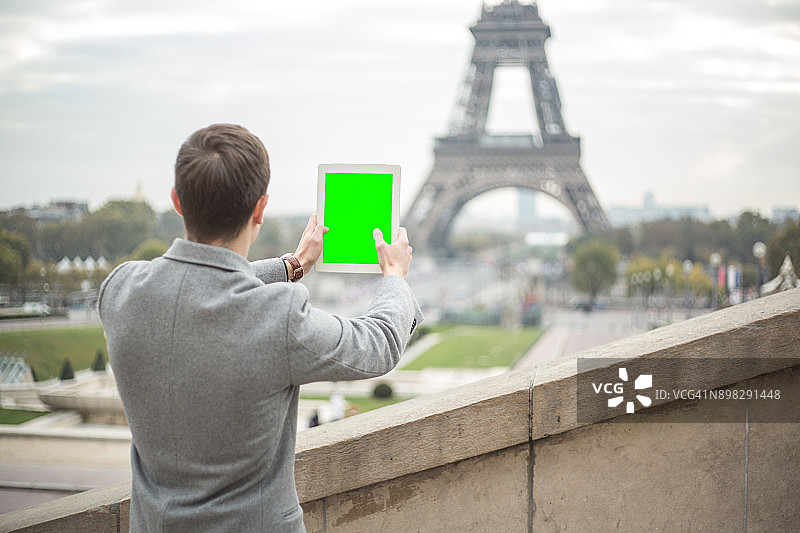 法国，一位年轻的商人正在用平板电脑拍摄埃菲尔铁塔图片素材