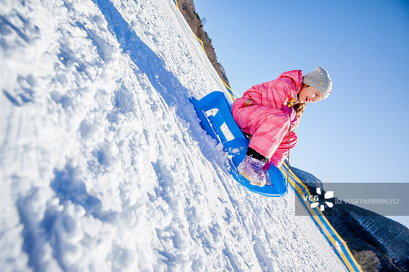 女孩穿着粉红色的冬天在雪地上玩图片素材
