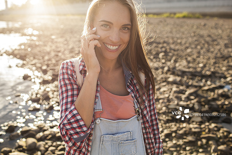 河边快乐年轻女子的手机肖像图片素材